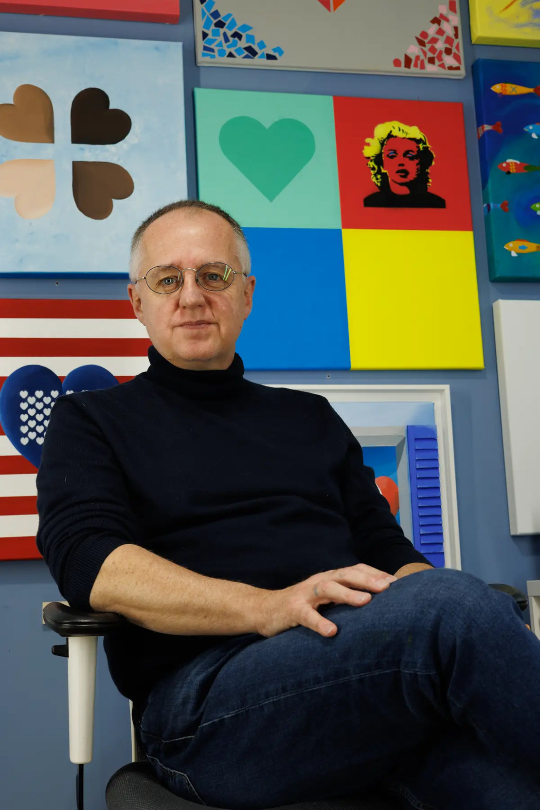 Sam Grudge seated with art collection