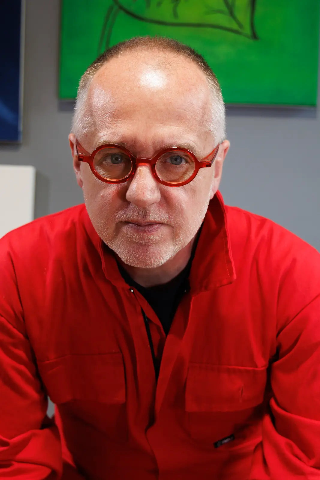 Sam Grudge in red coveralls and round red glasses.
