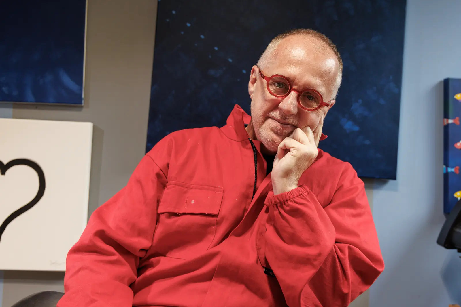 Sam Grudge in the studio wearing red coveralls and round red glasses.